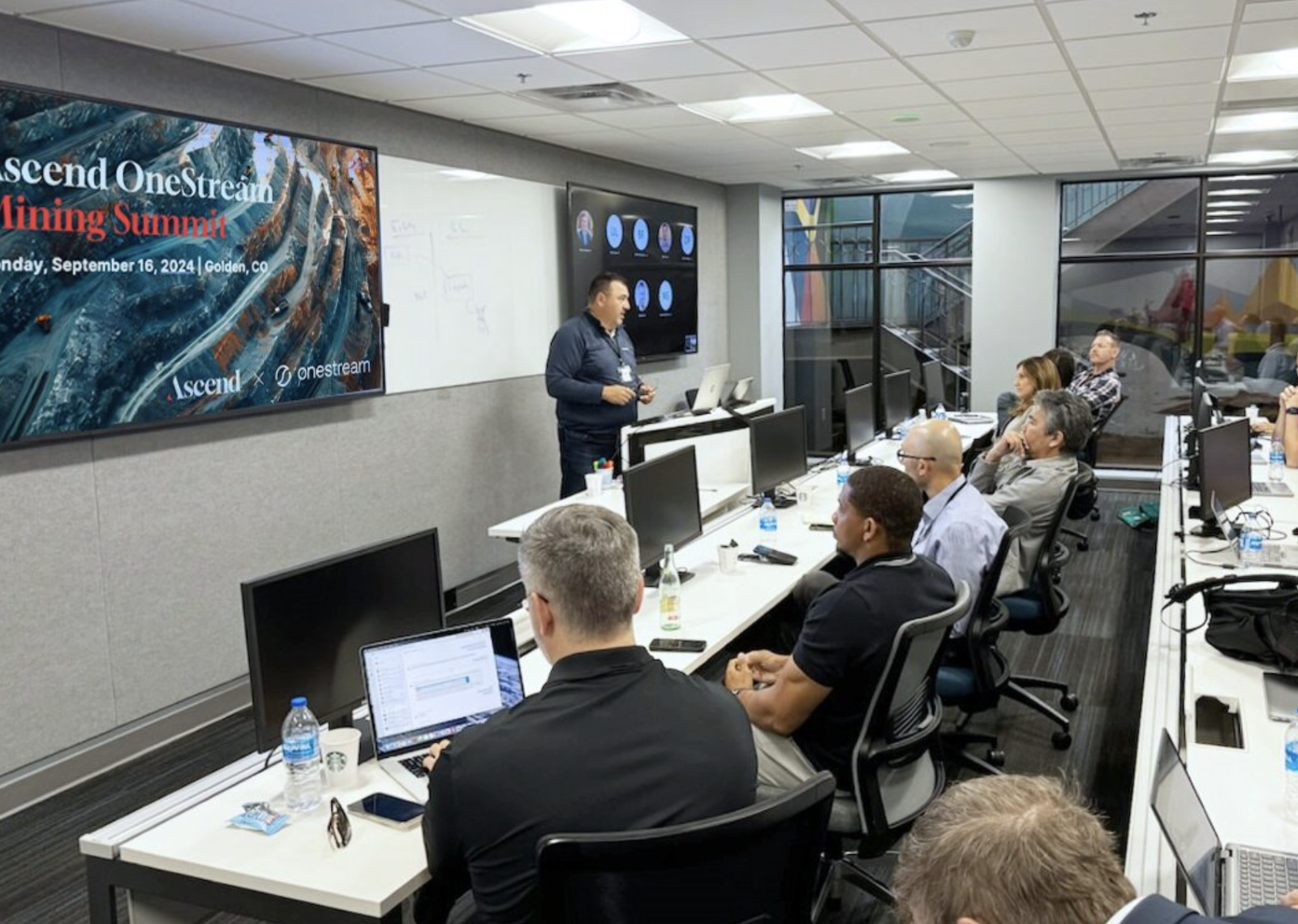 A person standing in front of a group of people in a room

Description automatically generated